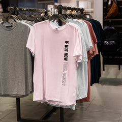T-shirts on a rack with one pink shirt featuring text in a store setting