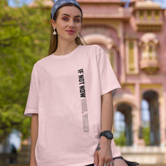 Woman wearing a pink t-shirt with text in front of an architectural building.