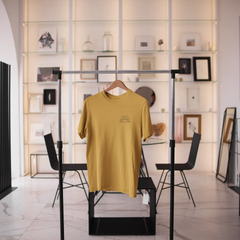 Yellow t-shirt on a hanger in a modern interior setting with furniture and decor.
