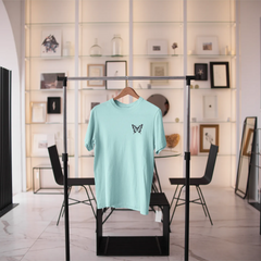 Light blue t-shirt with a butterfly design on a black rack in a modern interior setting.