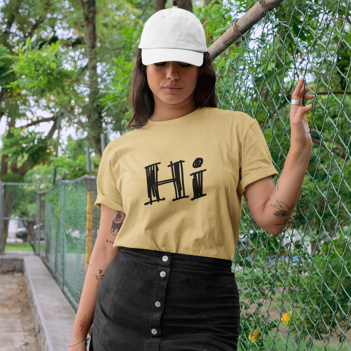 Woman wearing a yellow 'Hi' t-shirt and black skirt outdoors.
