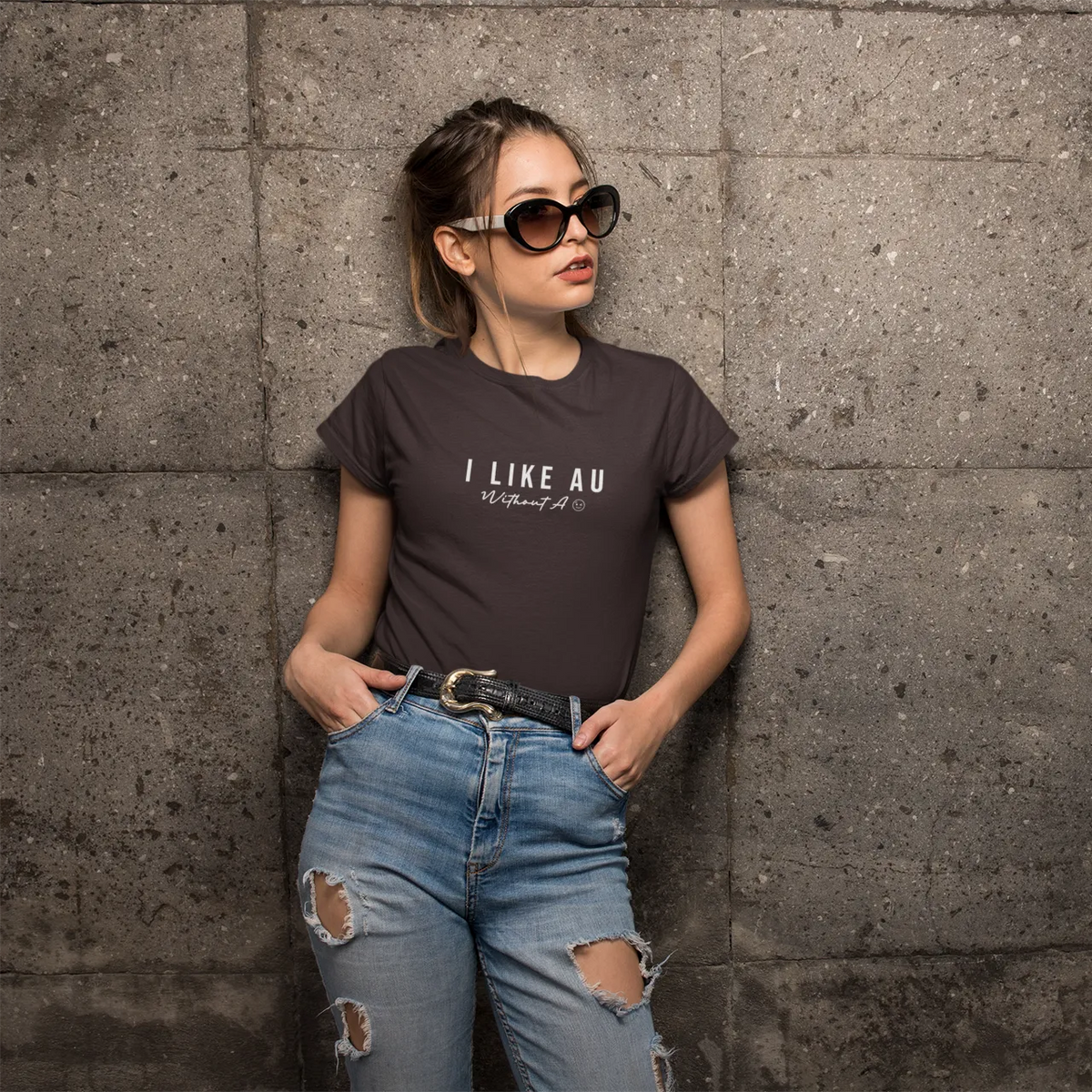 Woman wearing a t-shirt with text standing against a textured wall.