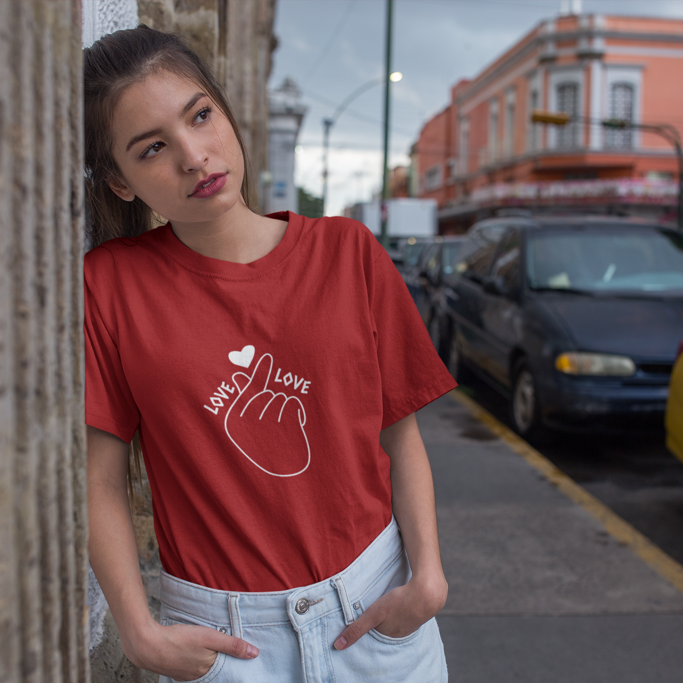 Woman wearing a red t-shirt with a graphic design on a city street.