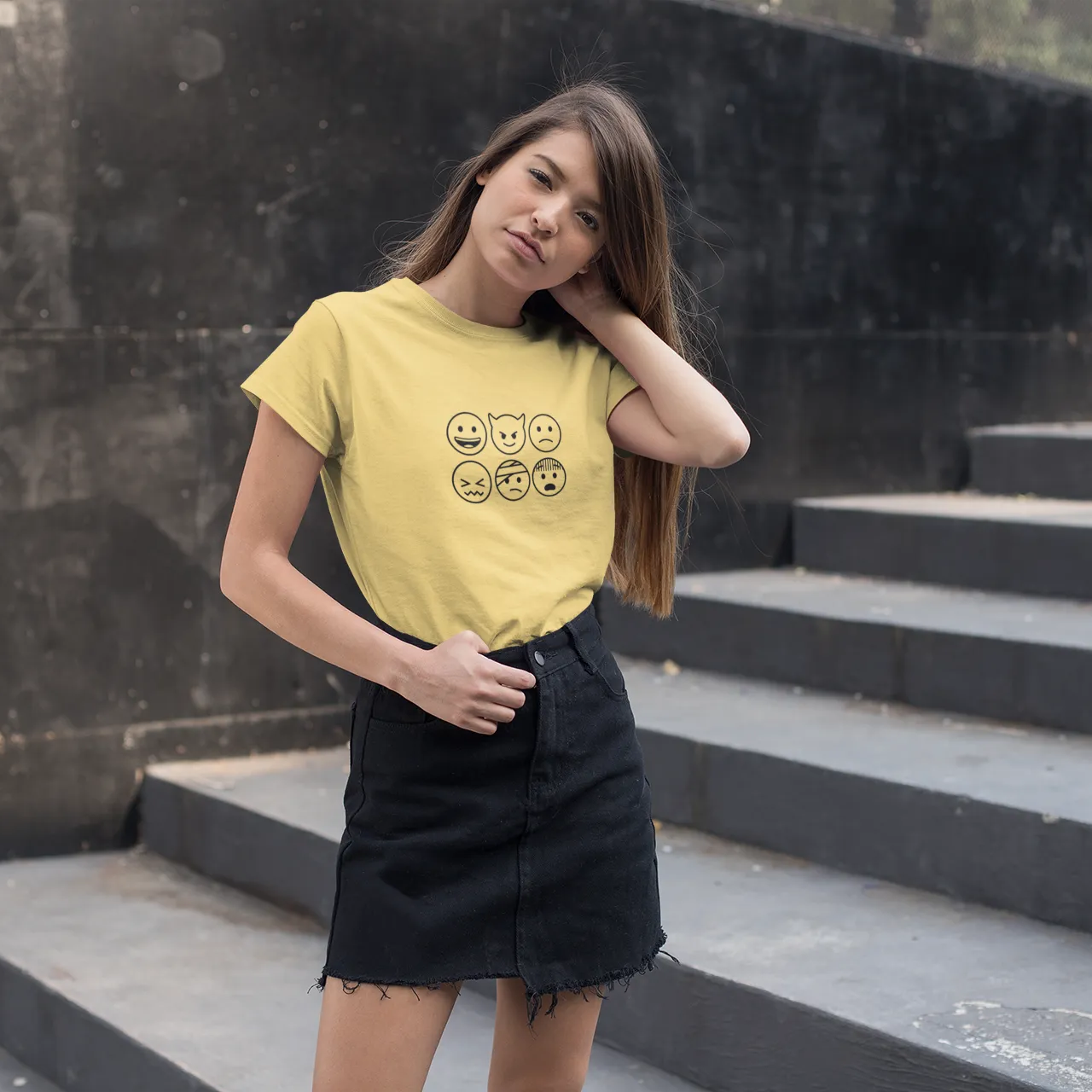 Woman wearing a yellow t-shirt with smiley face designs on black steps.