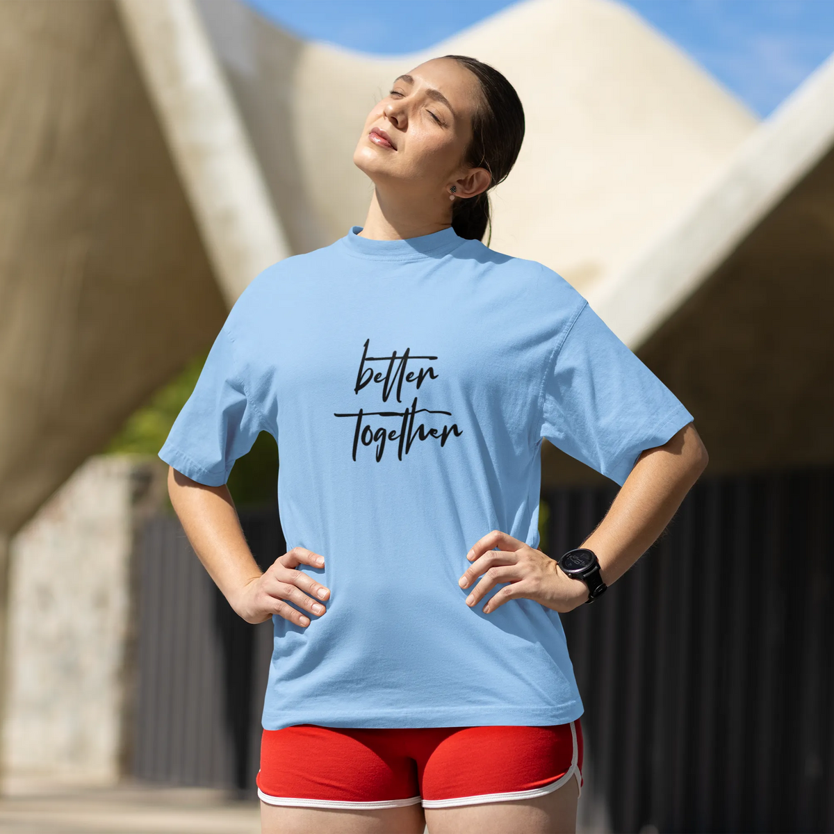 Woman wearing a light blue t-shirt with 'better together' text, standing outdoors.