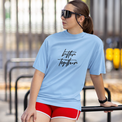 Woman wearing a light blue t-shirt with 'better together' text and red shorts, standing outdoors.