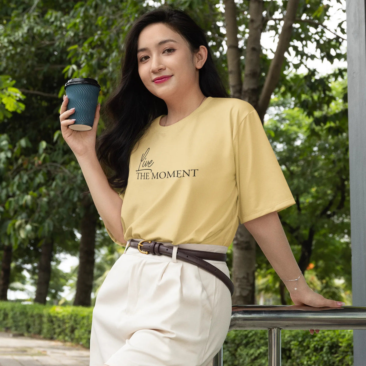 Woman holding a coffee cup outdoors with trees in the background