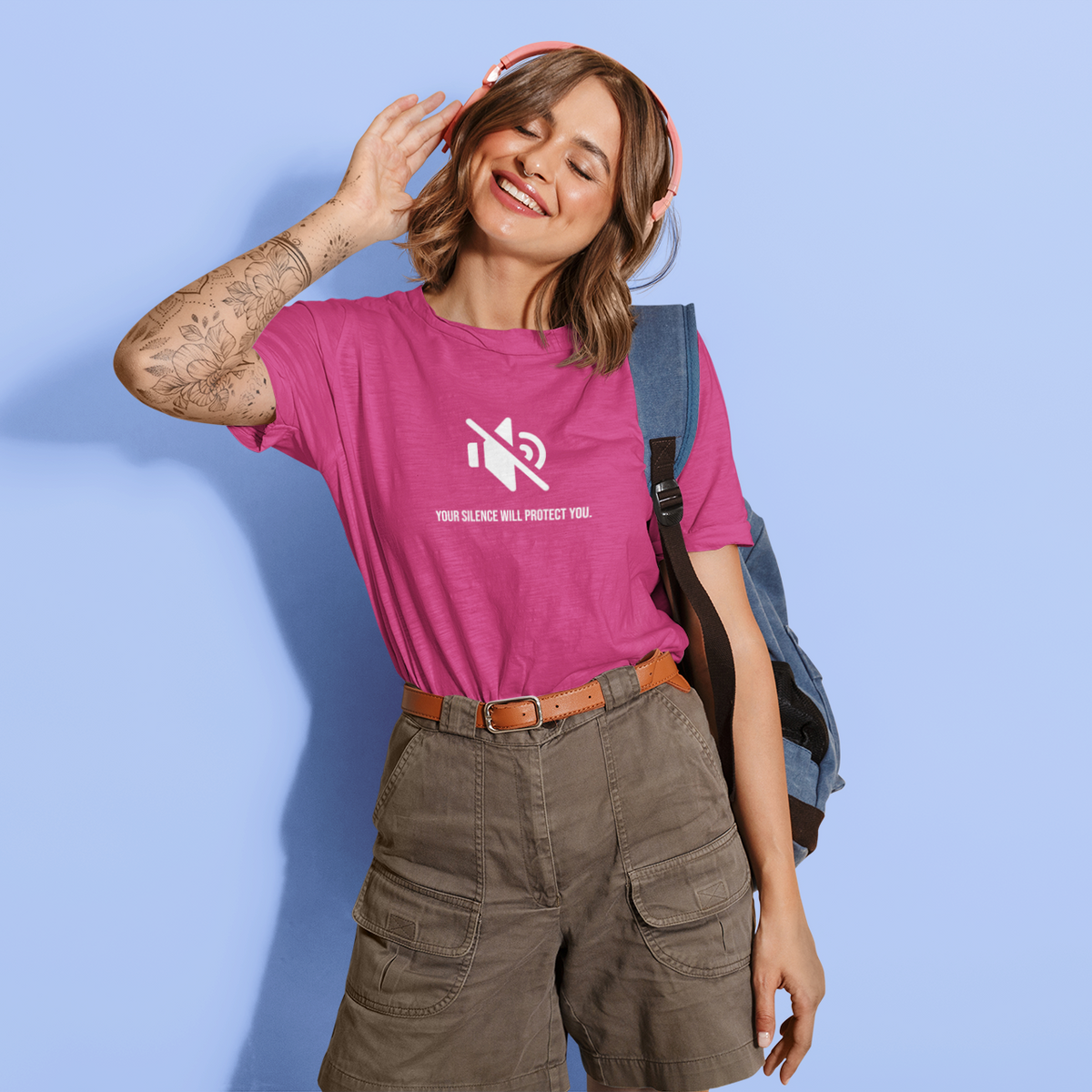 Woman wearing a pink t-shirt with a logo and text, standing against a light blue background