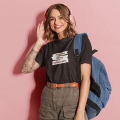 Woman wearing a black t-shirt with text, green pants, and a blue backpack against a pink background
