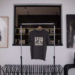Black t-shirt with graphic design hanging on a rack in a modern interior setting.