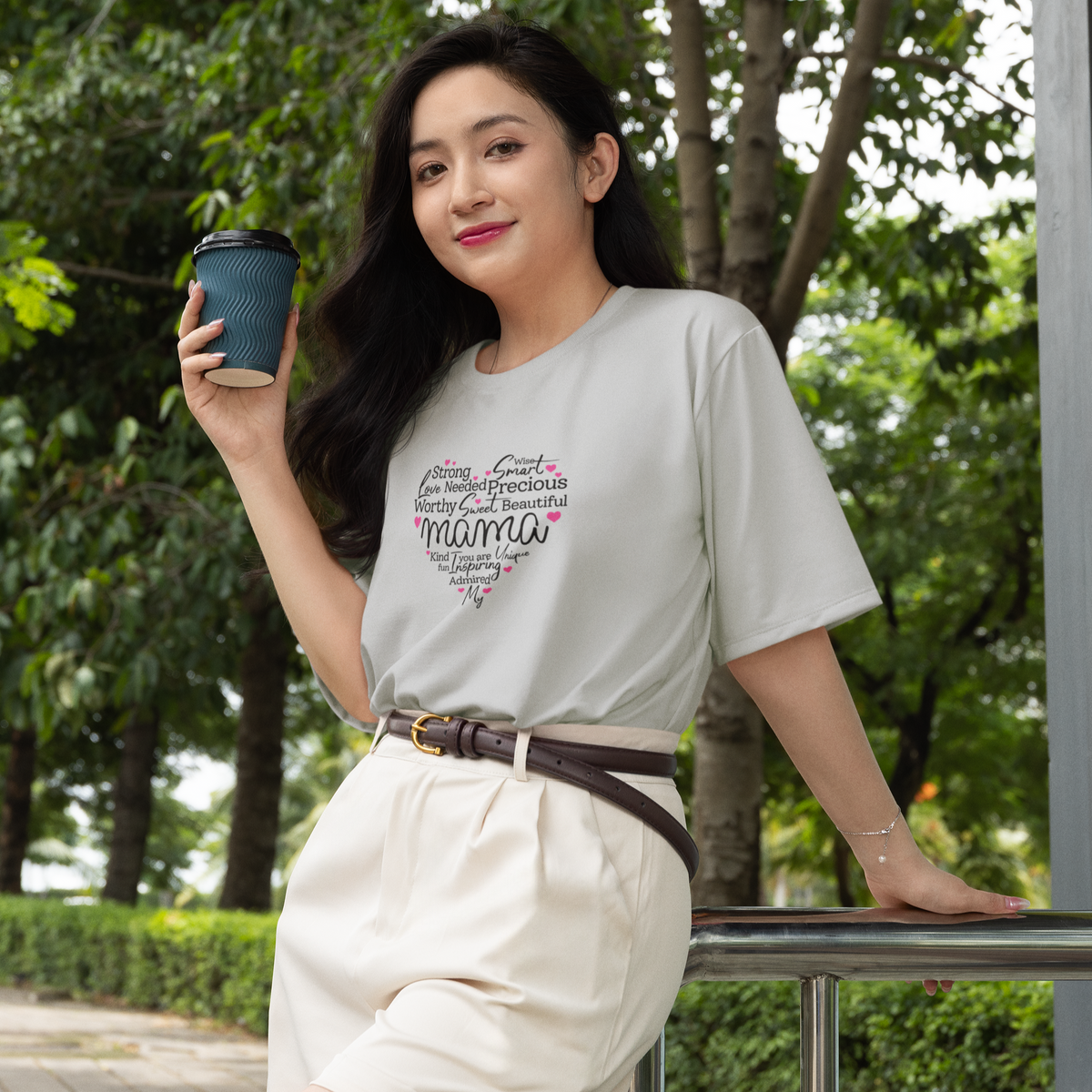 Woman holding a coffee cup outdoors with greenery in the background