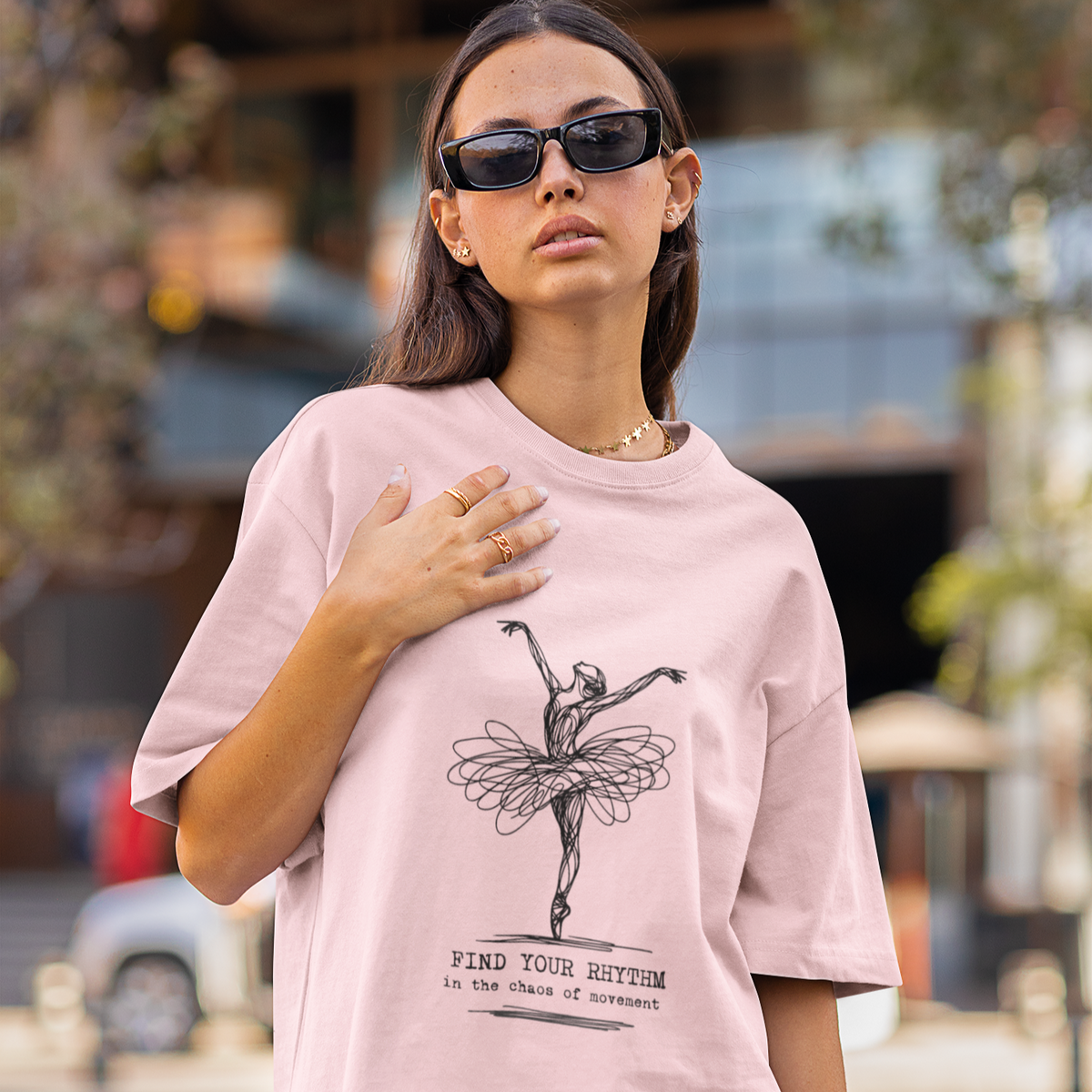 Woman wearing a pink t-shirt with a graphic design on a city street.