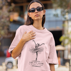 Woman wearing a pink t-shirt with a graphic design on a city street.