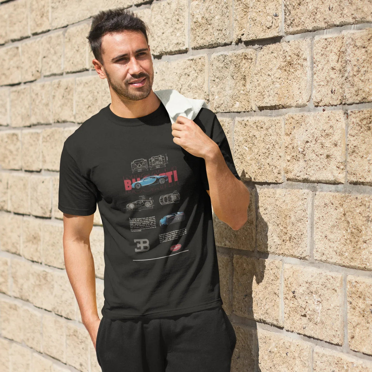 Man wearing a black t-shirt with graphic design against a stone wall