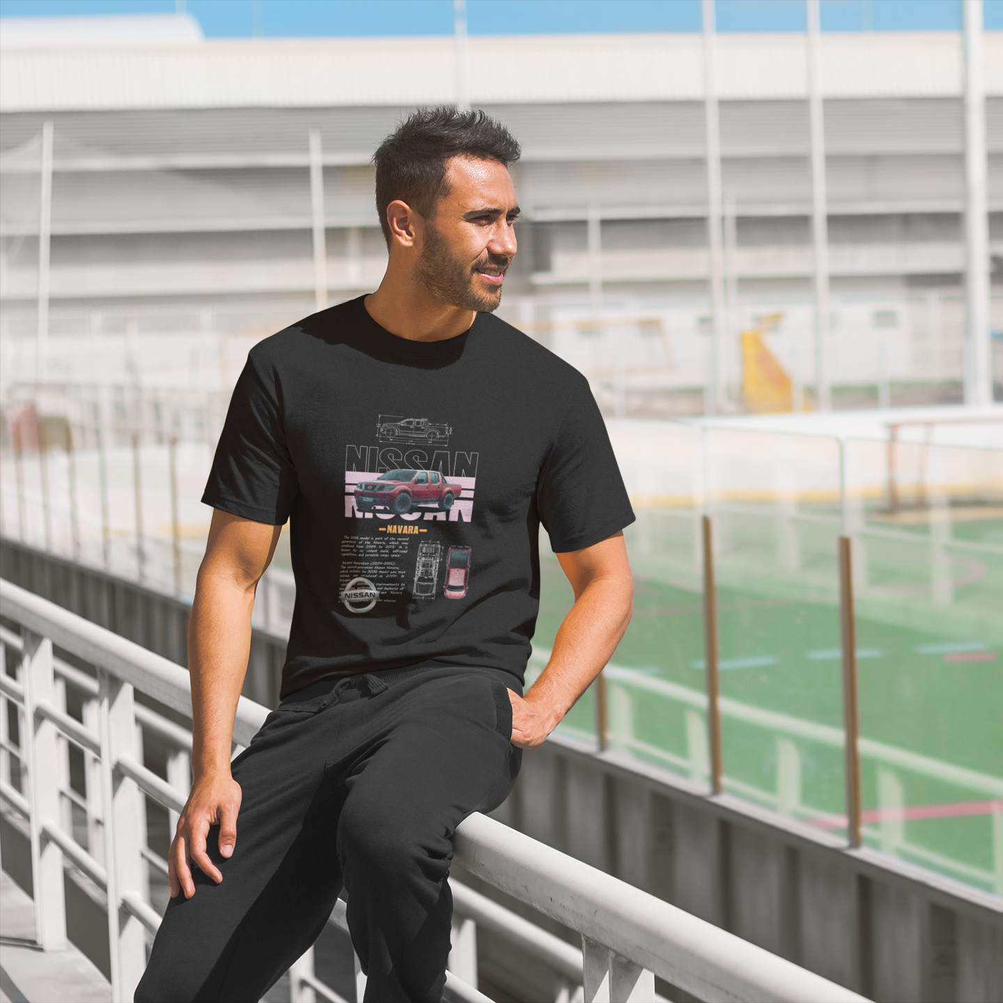Man wearing a black t-shirt with graphics, standing on a sports field.