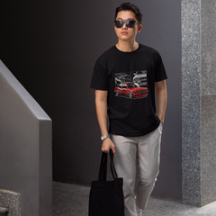 Man wearing sunglasses and a black t-shirt with a graphic design, holding a black bag, standing in an indoor setting.