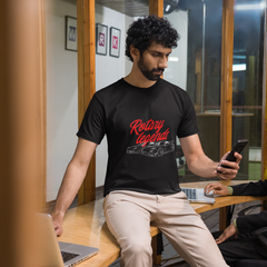 Two men in a casual setting, one using a phone and the other sitting at a table with a laptop.