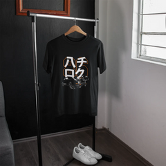 Black t-shirt with graphic design on a hanger in a room with a window.