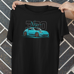 Black t-shirt with a blue car graphic and '370' text held by a person against a geometric patterned wall.