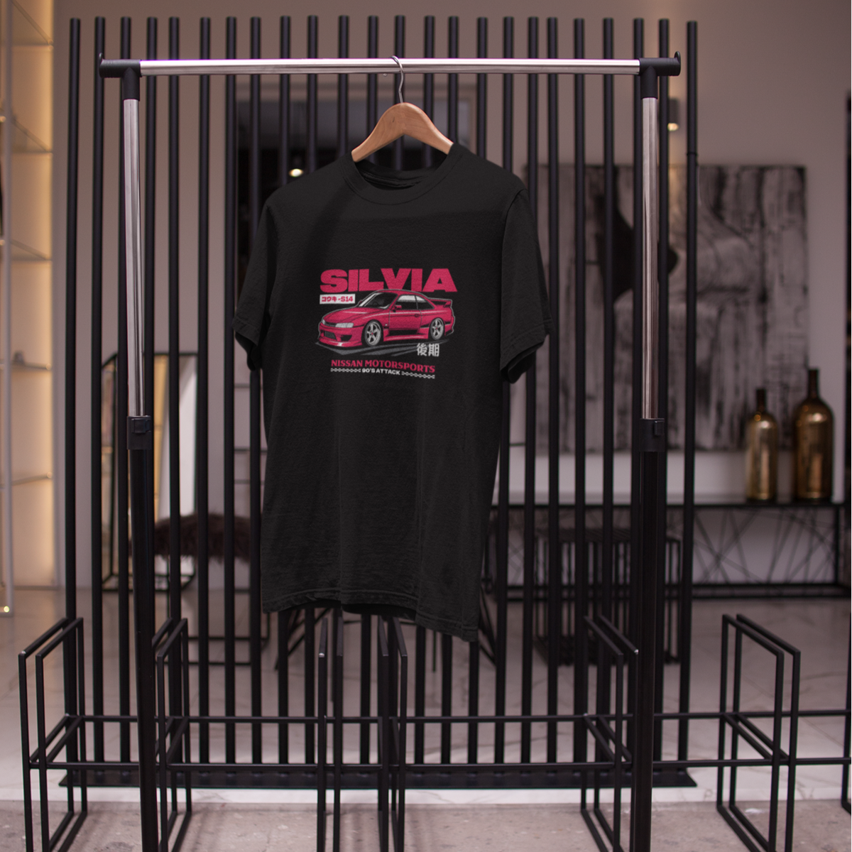 Black t-shirt with red graphic design on a black metal rack in a store setting.