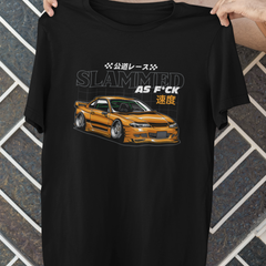 Black t-shirt with a car graphic and text held by a person against a tiled wall.