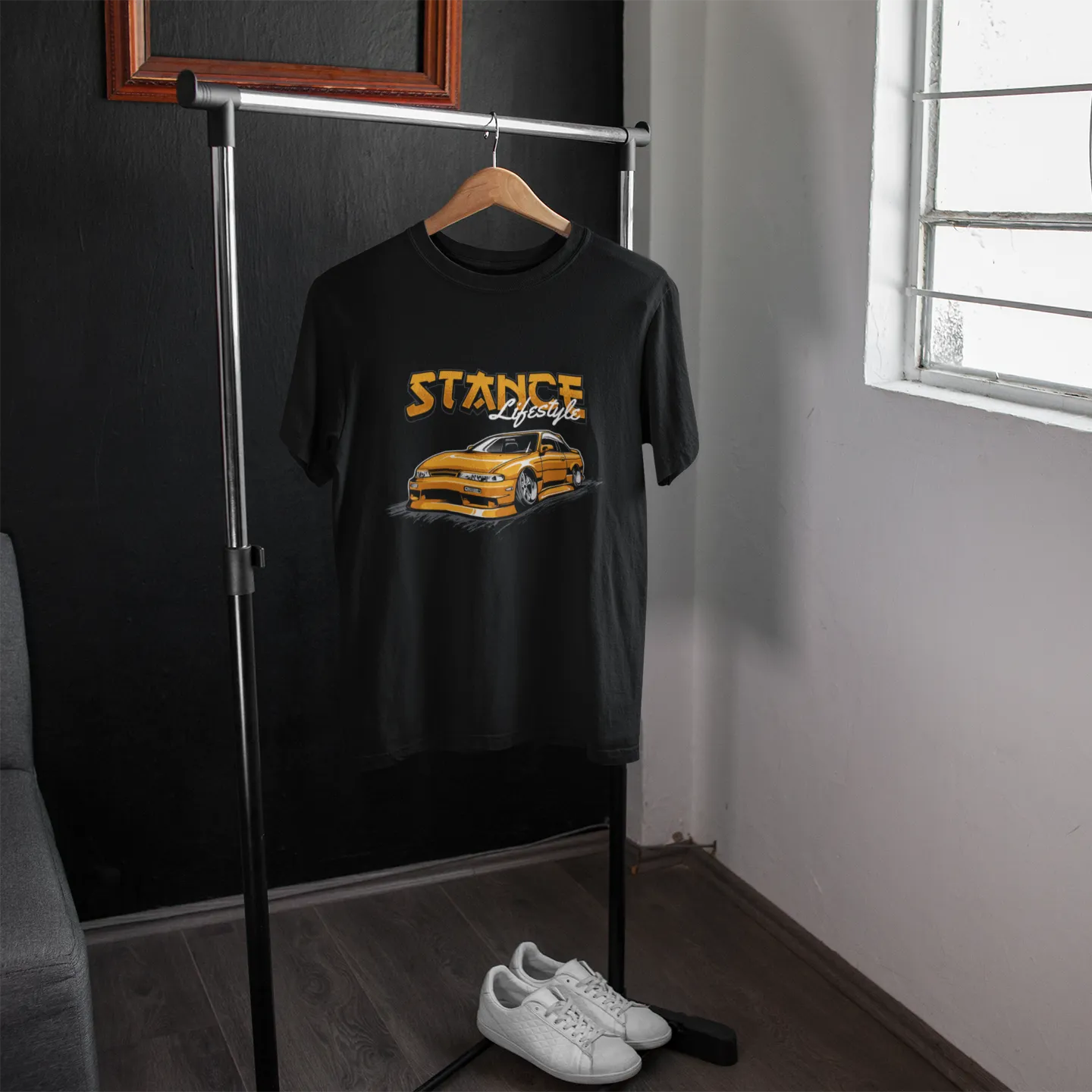 Black t-shirt with 'STANCE' graphic on a hanger in a room with a window.