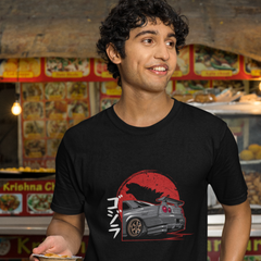 Man wearing a black t-shirt with a graphic design, standing in front of a food stall.