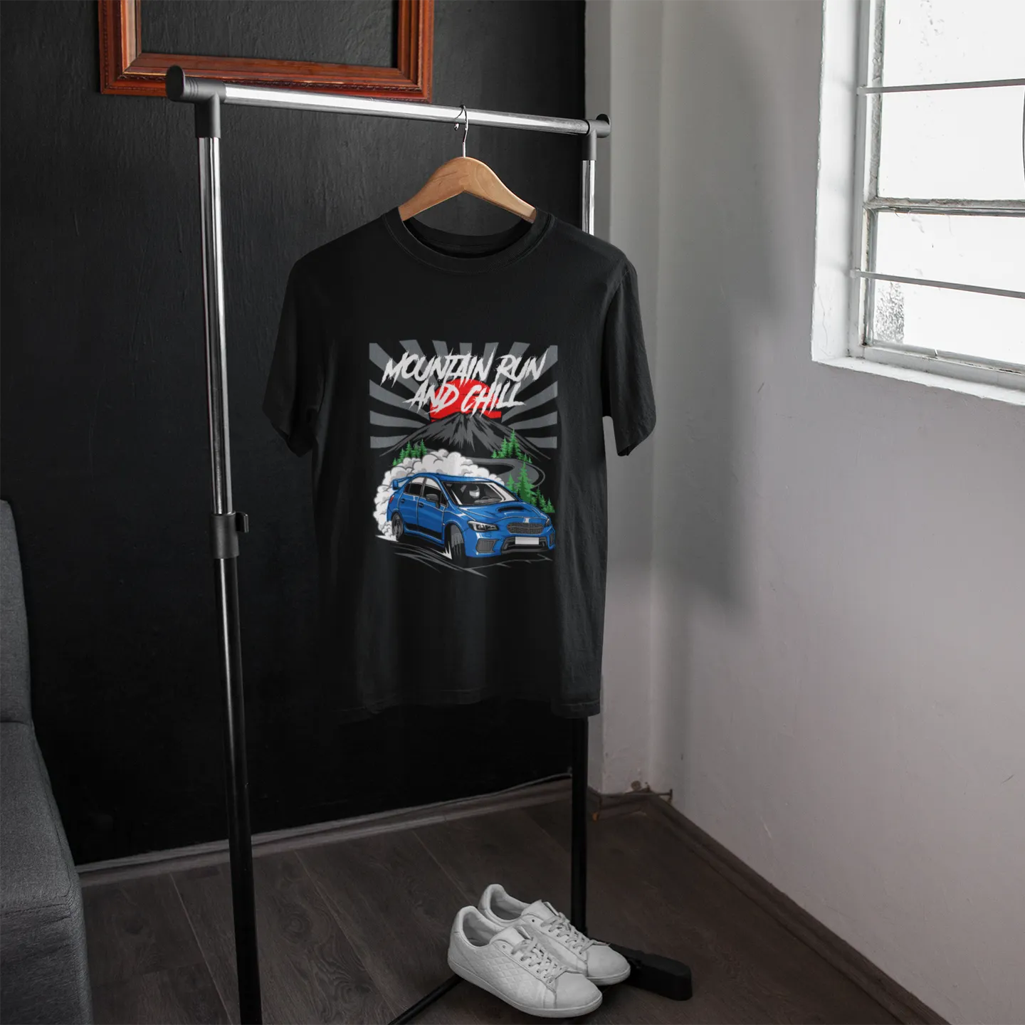 Black t-shirt with graphic design on a hanger in a room with a window.