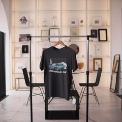 Black t-shirt with car graphic on a stand in a modern room with decor elements.
