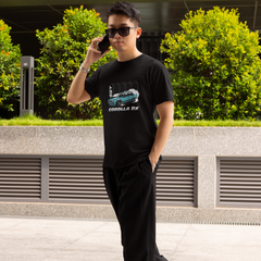 Man wearing a black t-shirt with a car graphic and sunglasses, standing outdoors.
