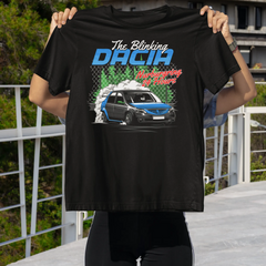 Person holding a black t-shirt with a graphic design of a car and text, outdoors.
