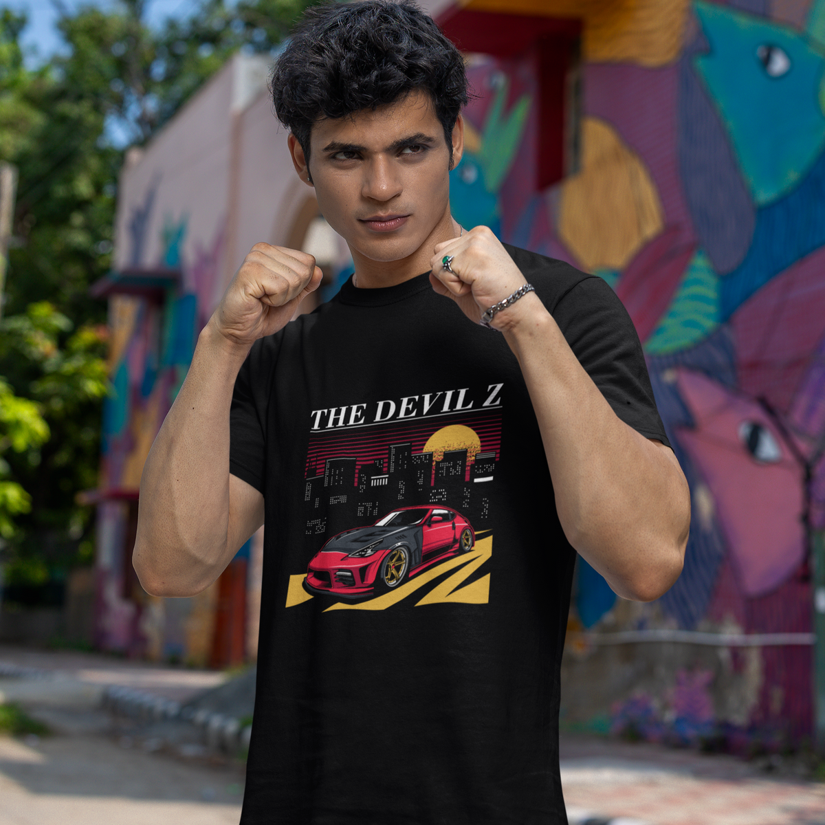 Person wearing a black t-shirt with a graphic design in front of a colorful mural.
