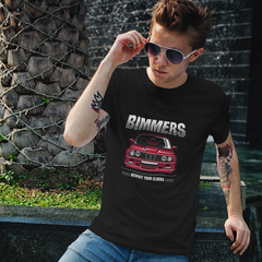 Man wearing a black t-shirt with 'Bimmers' graphic design, sitting outdoors.