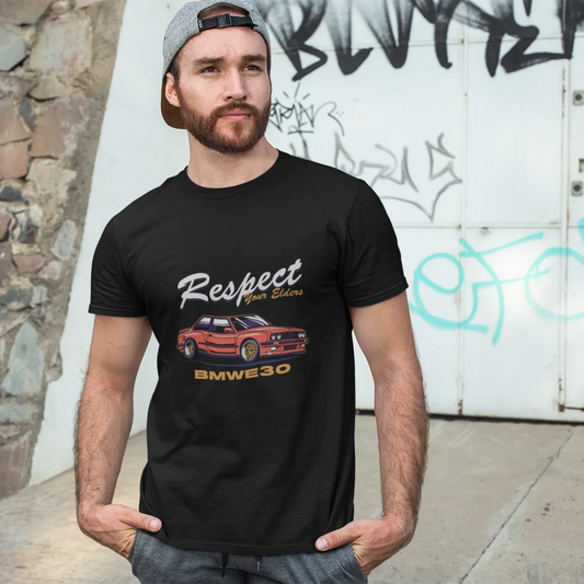 Man wearing a black t-shirt with a graphic design in front of a graffiti-covered wall.