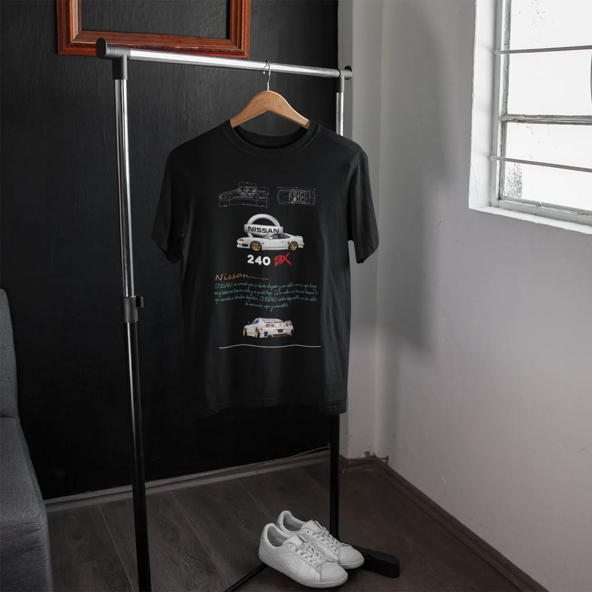 Black t-shirt with car design on a hanger in a room with a window.