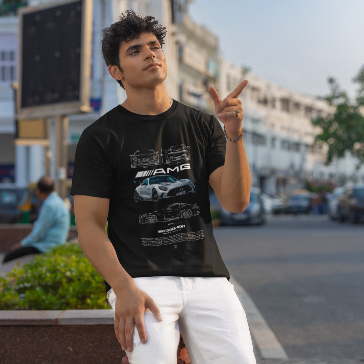 Man wearing a black t-shirt with car graphics on a city street