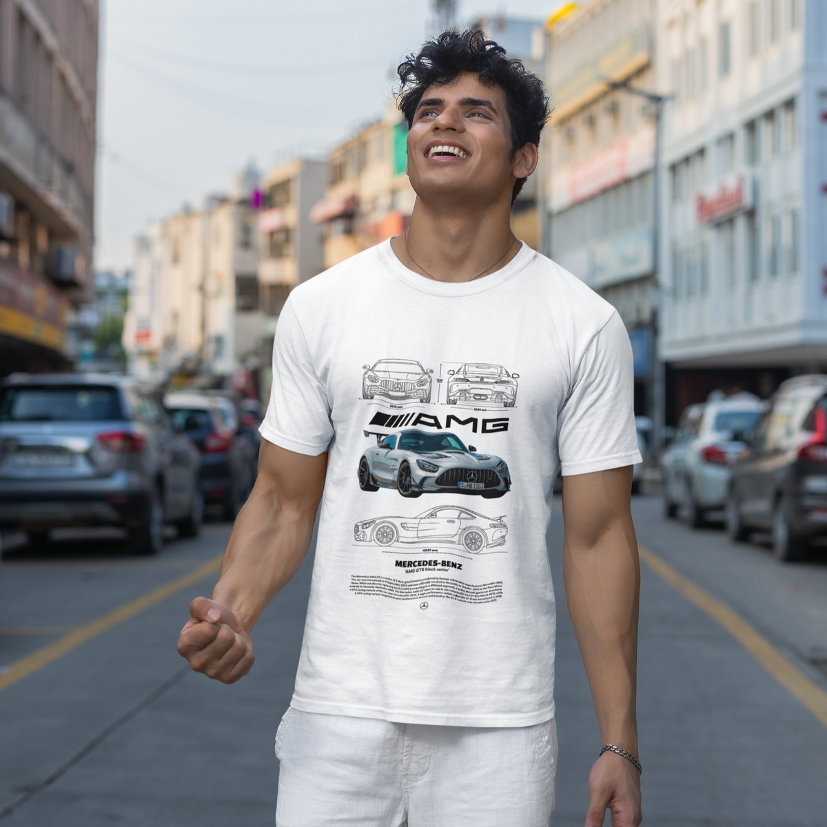 Man wearing a white t-shirt with a car graphic on a city street