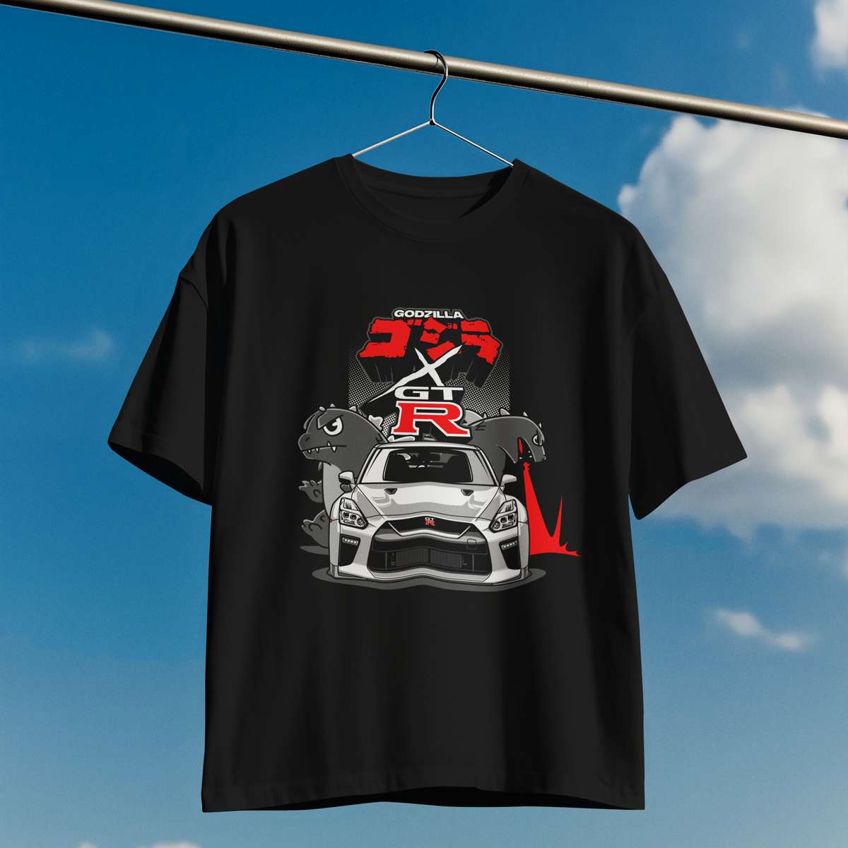 Black t-shirt with car graphic design hanging against a blue sky