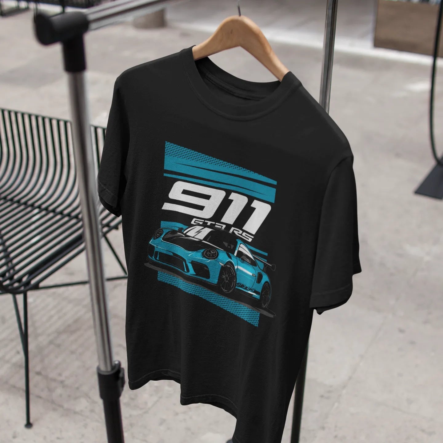 Black t-shirt with a blue and white graphic design on a hanger against a neutral background.
