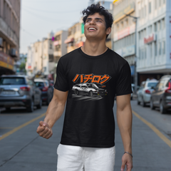 Man wearing a black t-shirt with orange graphics on a city street.