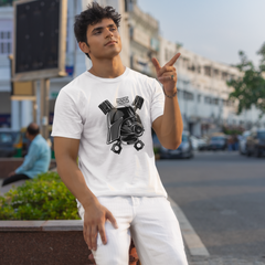 Man in a white t-shirt with a graphic design, standing on a street with buildings and cars in the background.