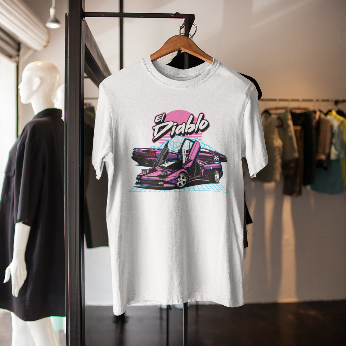 White t-shirt with a graphic design of a car and 'El Diablo' text on a hanger in a store setting.
