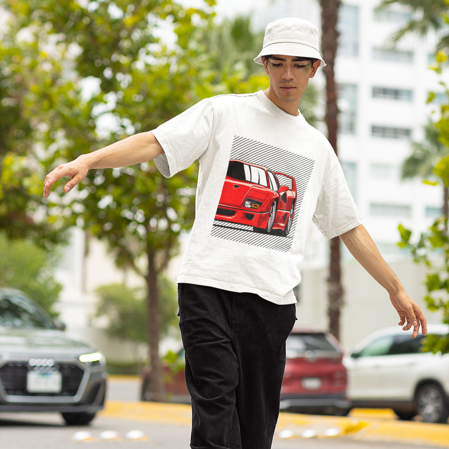 Person wearing a white t-shirt with a graphic design, black pants, and a white cap on a street.