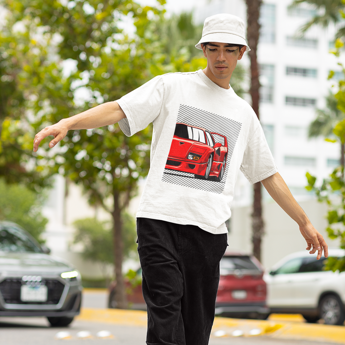 Person wearing a white t-shirt with a graphic design, black pants, and a white cap on a street.