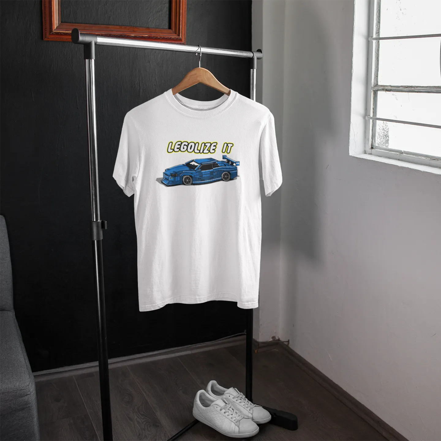 White t-shirt with graphic design on a hanger in a room with a window.