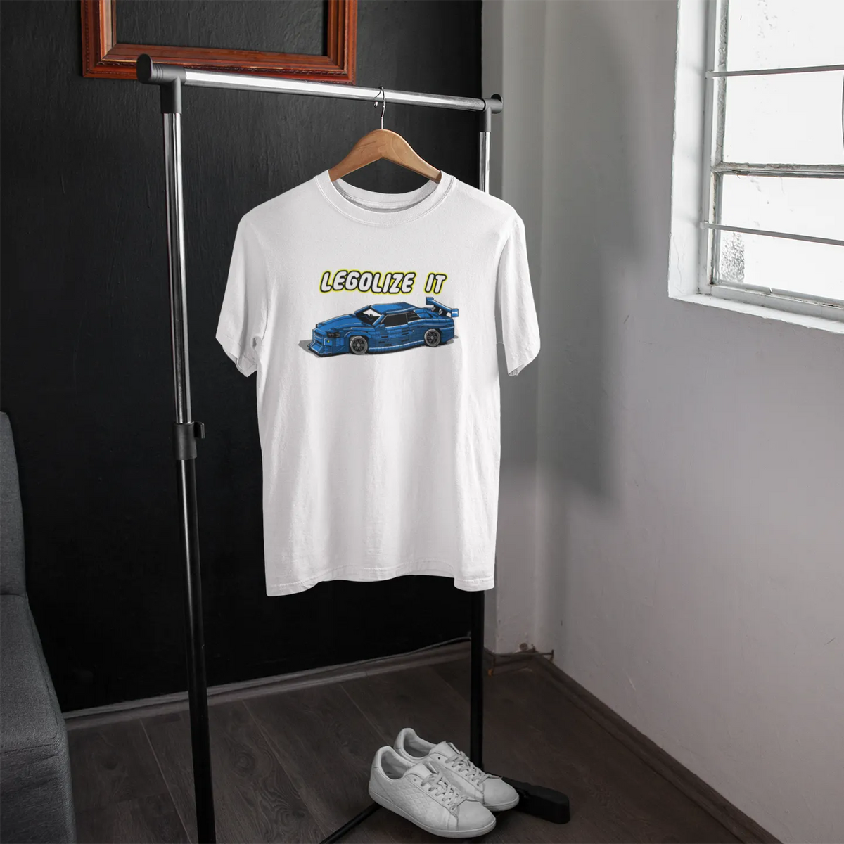 White t-shirt with graphic design on a hanger in a room with a window.