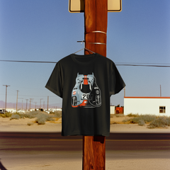 Black t-shirt with a graphic design hanging on a wooden pole in a desert landscape.