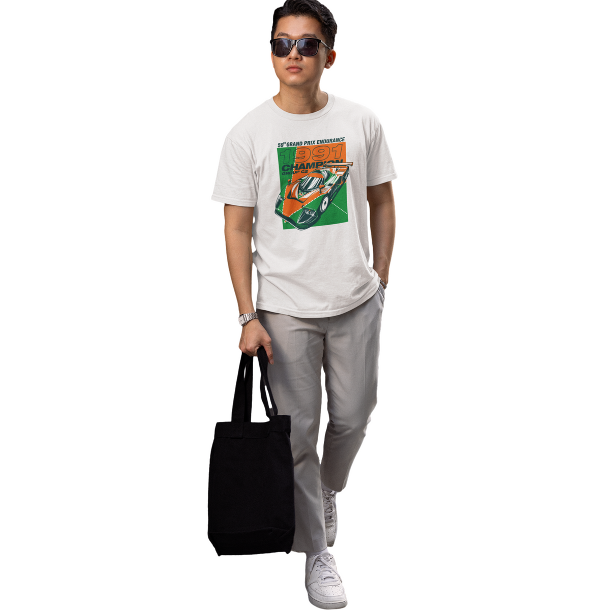 Person wearing a graphic t-shirt and holding a black tote bag on a white background