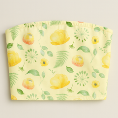 Yellow tube top with floral and leaf pattern on a light gray background