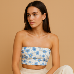 Woman wearing a floral strapless top and beige pants on a beige background